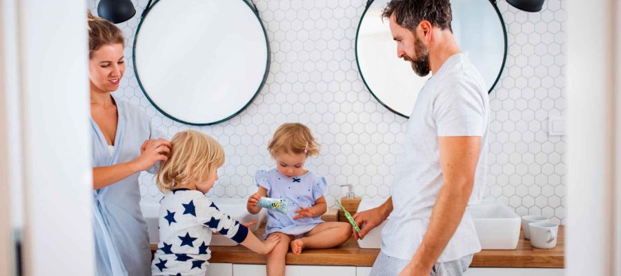 Young family with two small children indoors in bathroom, talking.